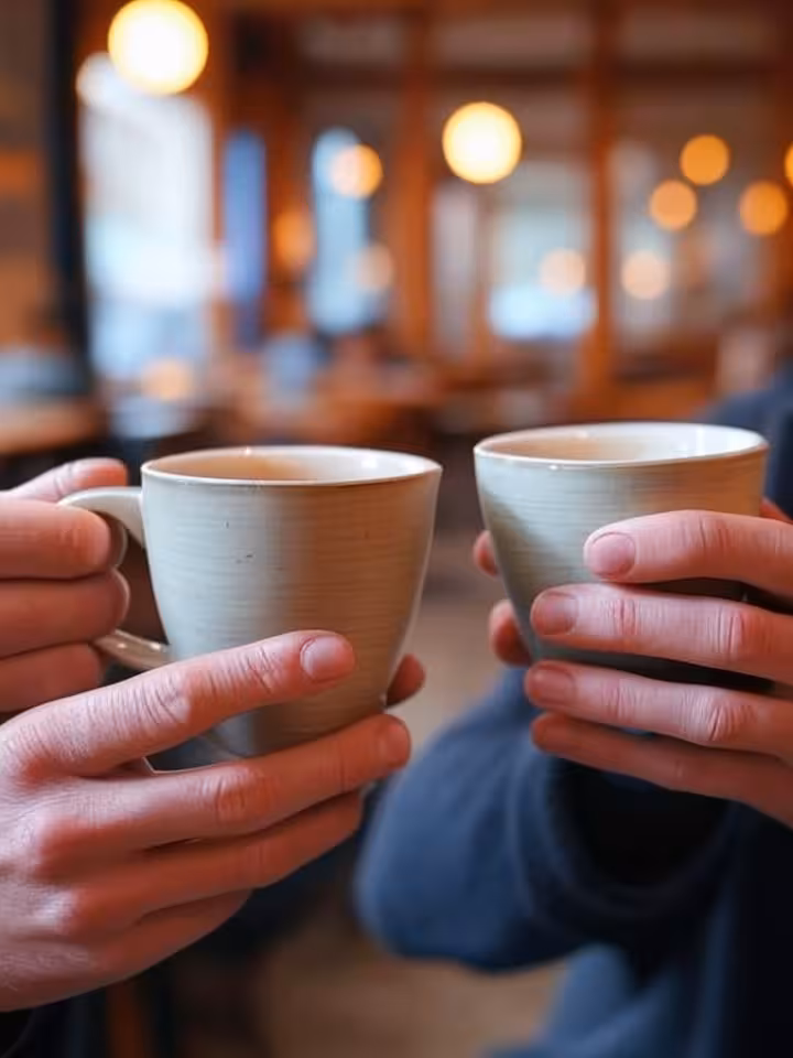 Close-up of two people's hands holding coffee cups during deep conversation, soft focus background o